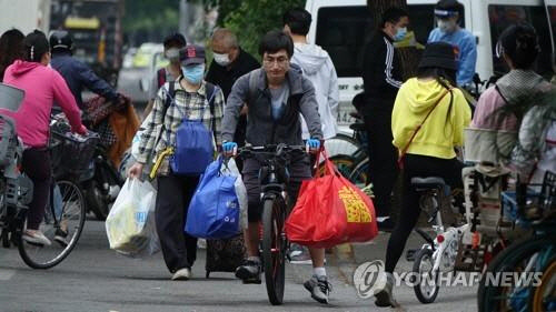 지난 19일 중국 상하이 창닝구의 까르푸 매장 앞에서 장을 본 시민들이 물건을 담은 봉지를 들고 귀가하고 있다. <상하이=연합뉴스>